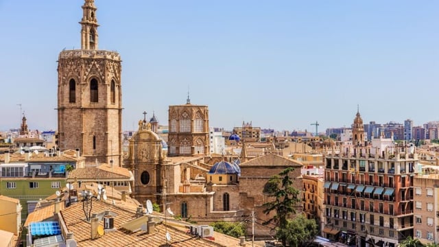 A panoramic view of Valencia’s historic centre, showing cathedral towers, terracotta rooftops and modern city buildings in the distance.