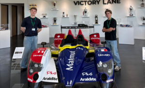 James Brook and another student standing next to a red, white and blue Formula 1 car.