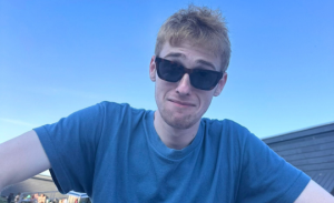 James Postlethwaite wearing sunglasses and a blue T-shirt