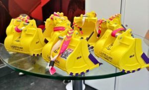 Yellow mini digger bucket toys with ribbons attached sitting on a glass table 