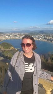 Sarah standing at a high viewpoint overlooking a large bay, with the city and hills in the distance