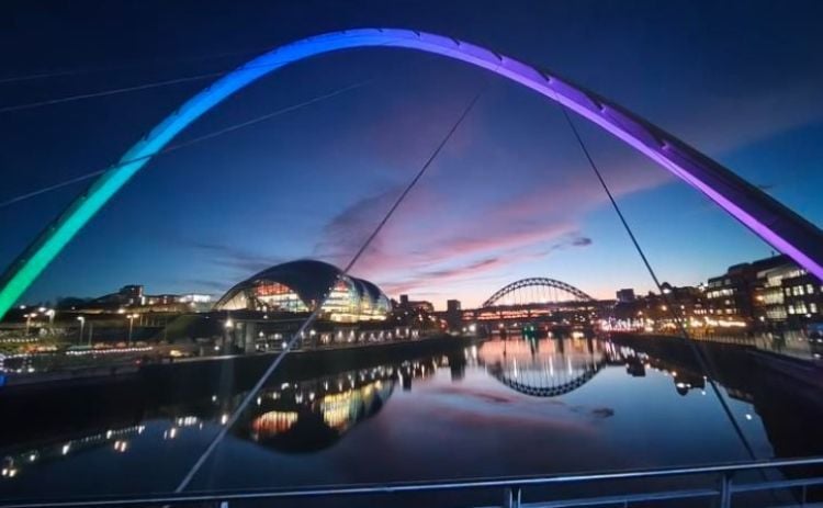 Newcastle’s iconic bridges illuminated against the evening sky, reflected in the River Tyne.